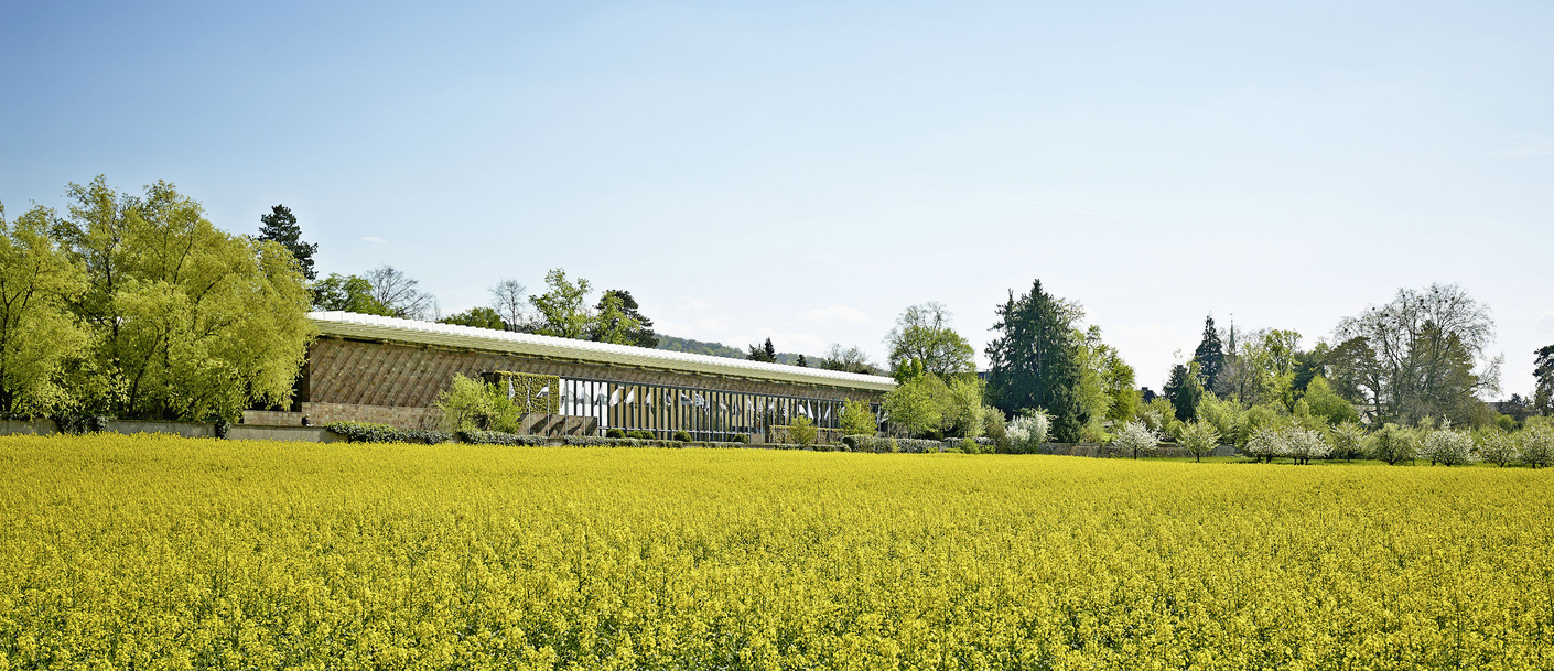Blick von den benachbarten Feldern auf den Wintergarten an der Westseite des Piano-Gebäudes.