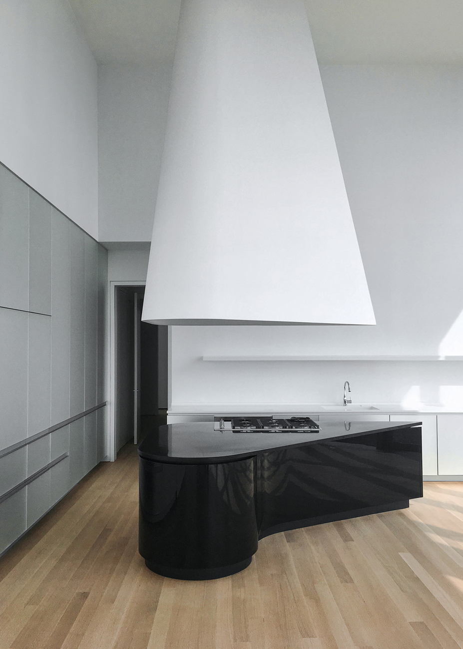 With their fluid shapes the glossy black kitchen blocks with granite countertops fit the layout of the space perfectly.