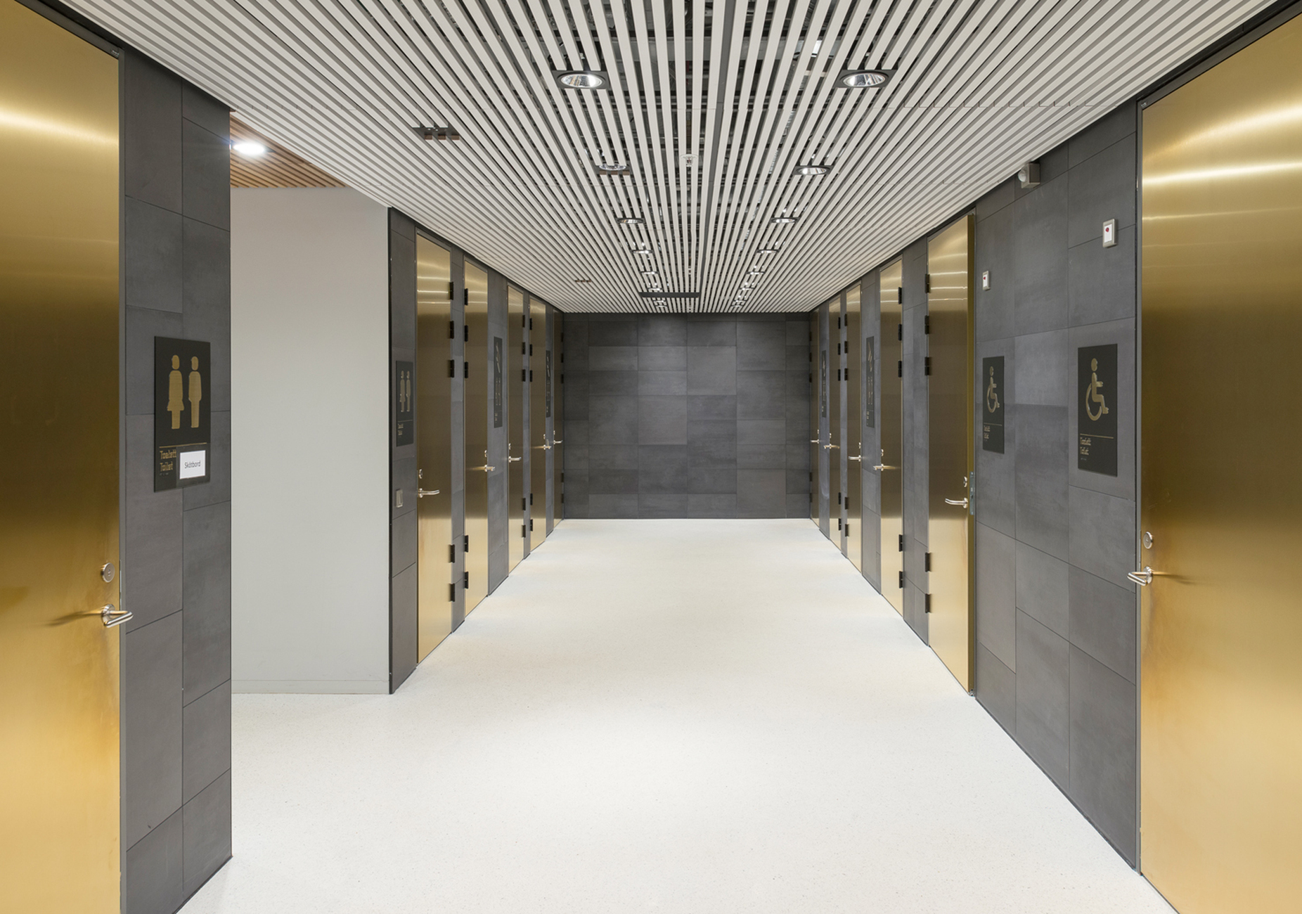 An den Wänden der Zugangsbereiche setzen die Fliesen "Terra Tones 216 V" von Mosa im Kontrast zu den hellen Böden und Decken die Struktur der Fassade fort.