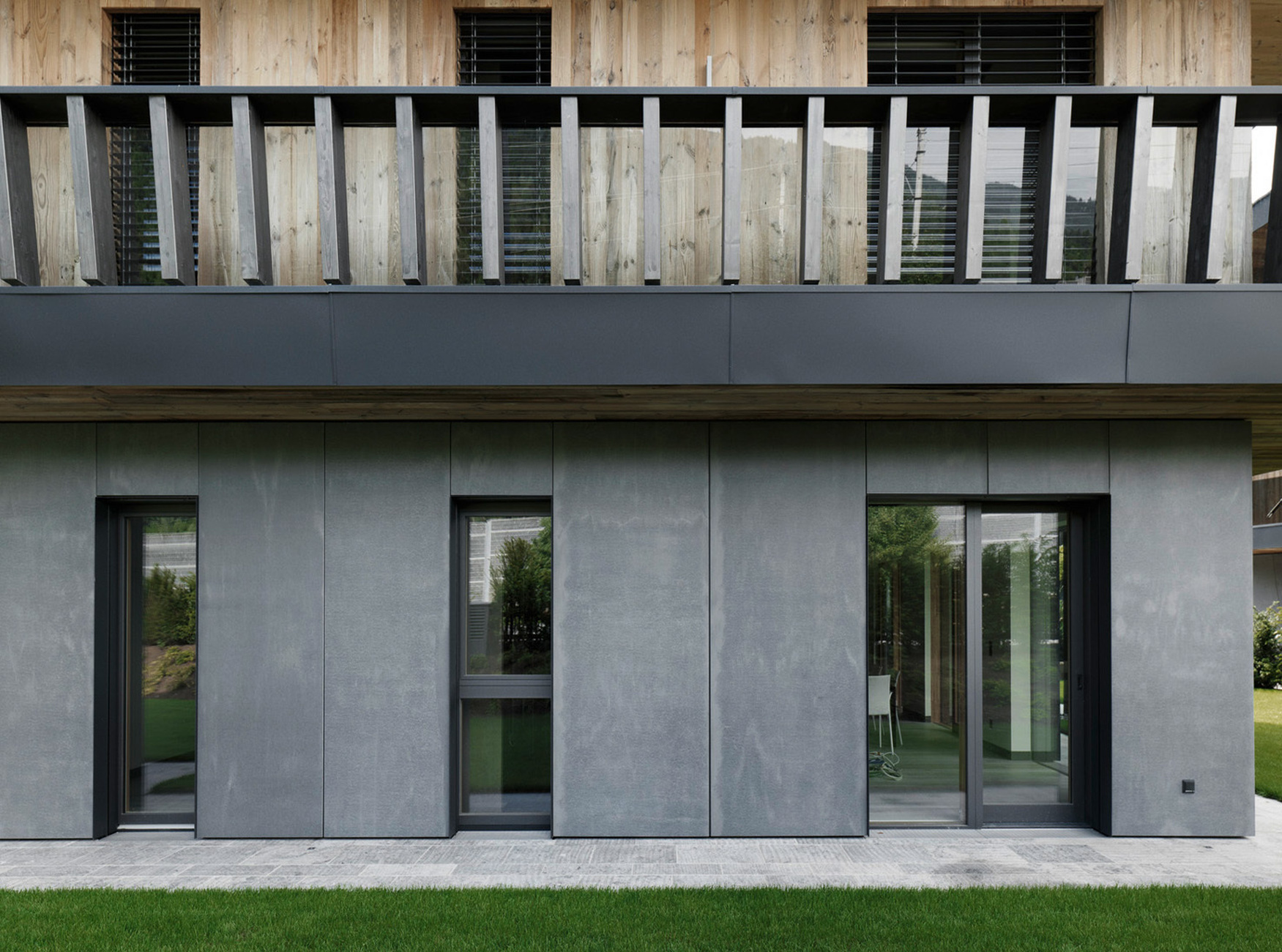While the upper stories are clad in wood, the ground floor relies on anthracite-colored panels made of fibreC, fiberglass concrete.