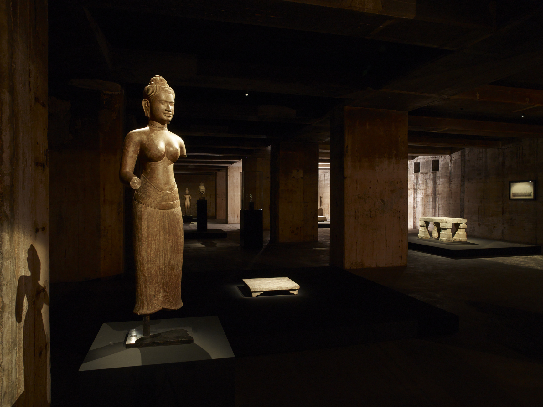 Installation view of The Feuerle Collection, Khmer Female Divinity and Stone Platform China, Han dynasty (2nd BC- 2nd AD), Conglomerate, Height approx. 30 cm. In the background: Rectangular table with four legs , Early Qing dynasty, 17th Century, White marble , Height approx. 80cm, Weight approx. 800kg and work by Adam Fuss.