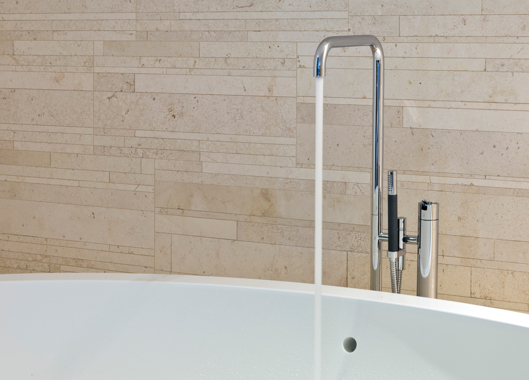 Das klassische Design von Arne Jacobsen brilliert in Form der freistehenden Wannenarmatur mit Handbrause Vola FS1.