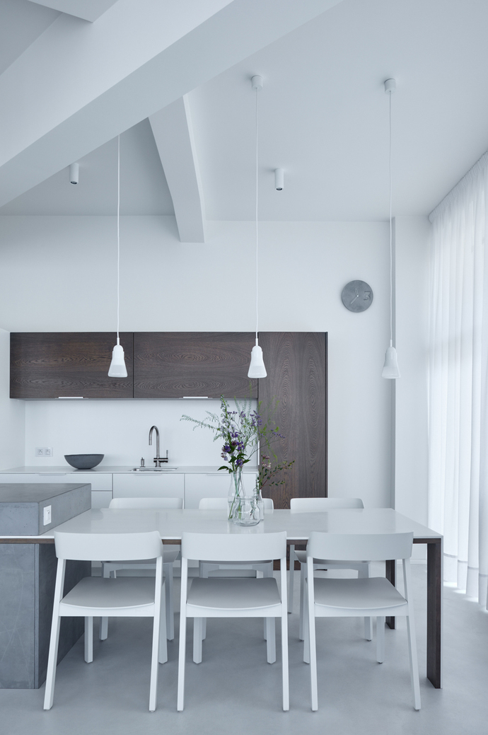 A white table top made of the Corian mineral material connects to the kitchen island and is served by six white "Merano" chairs from clay to the dining table.