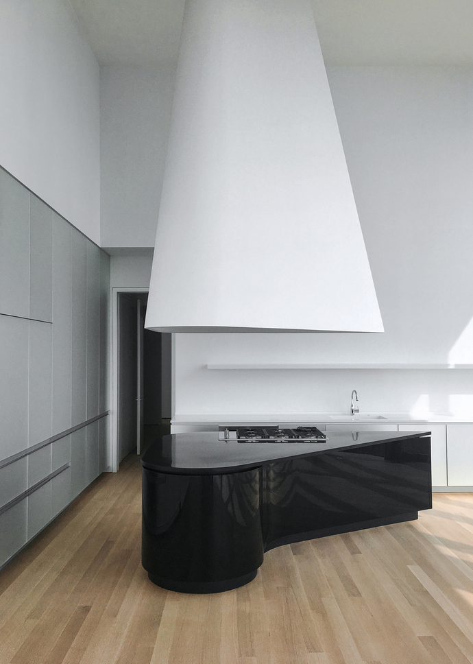 With their fluid shapes the glossy black kitchen blocks with granite countertops fit the layout of the space perfectly.