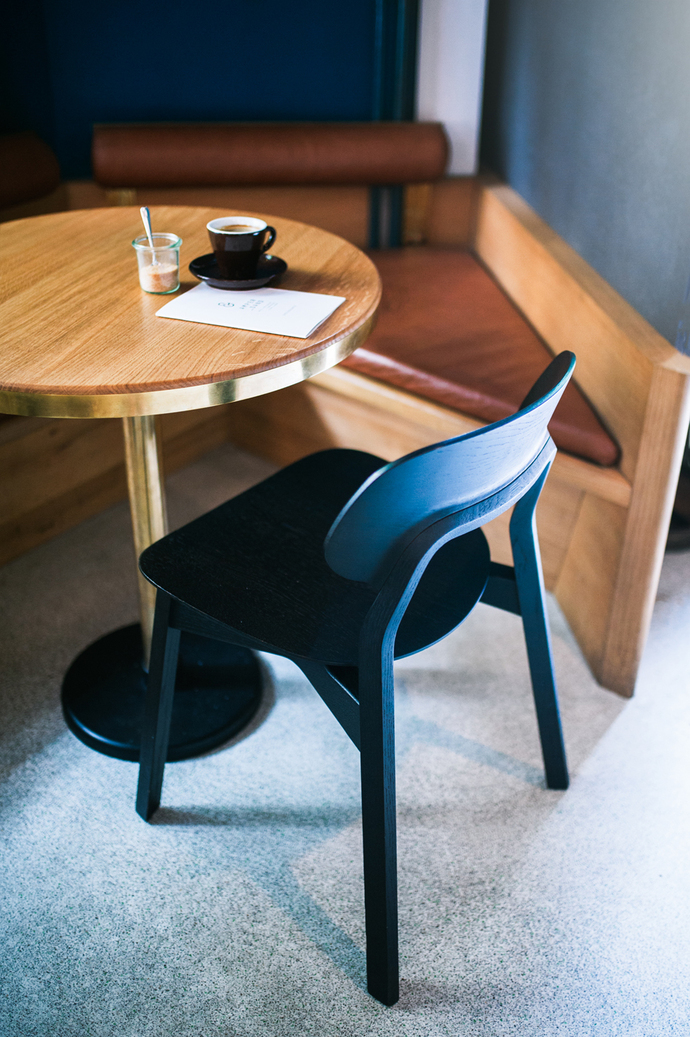 Zu den anthrazit- und salbeifarbenen Wandfarben und Polstern setzen metallische Details und helles Holz einen edlen Kontrast.