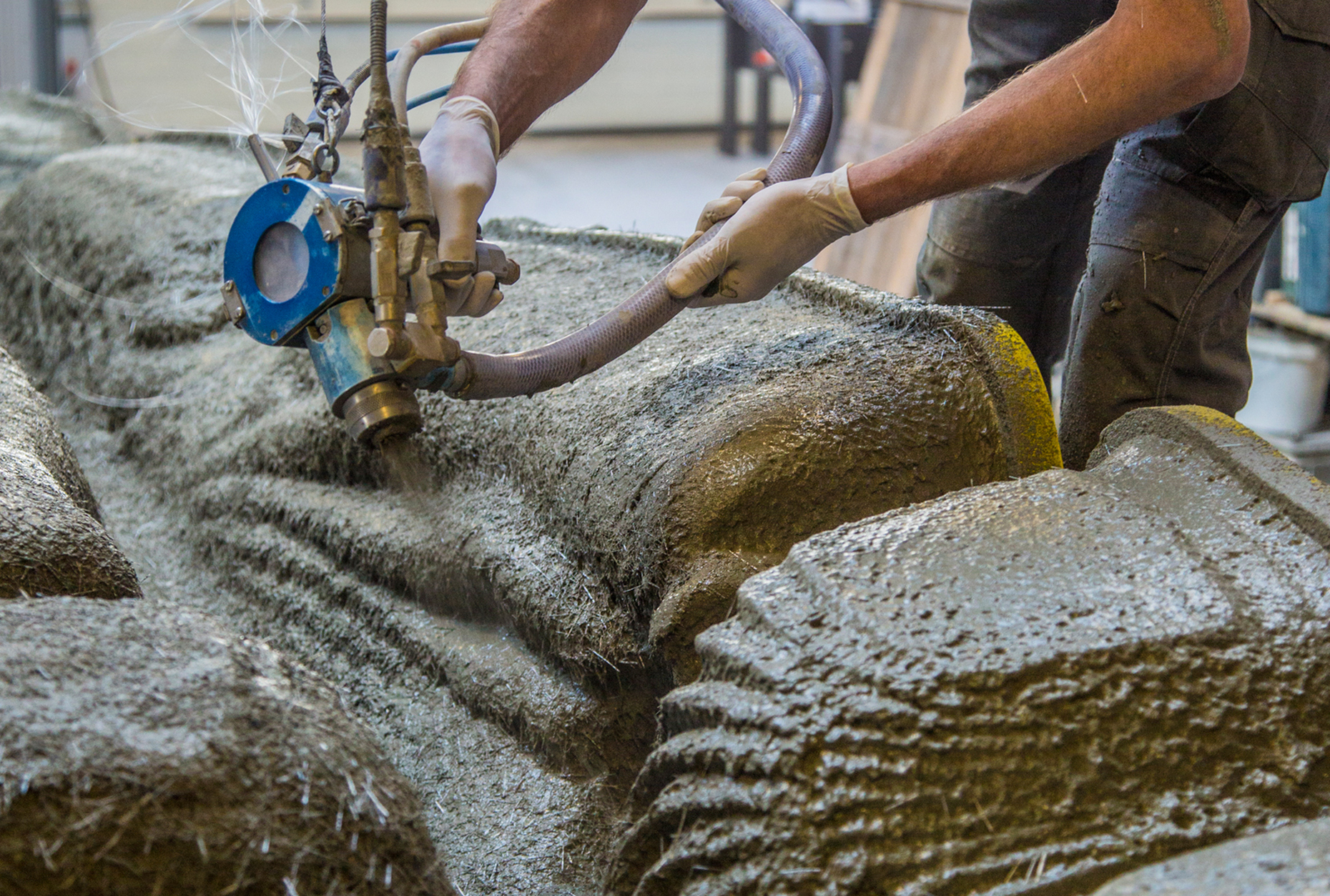 Glass-fibre reinforced concrete being sprayed on the 3D printed formwork in several consecutive layers.